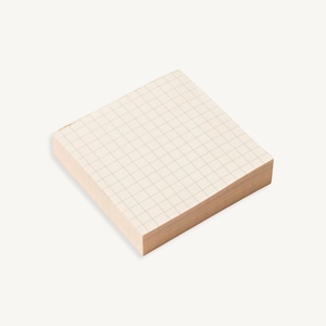 May include: A stack of white gridded sticky notes with a light brown backing.