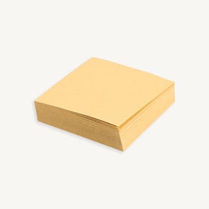 May include: A stack of square, light brown sticky notes.