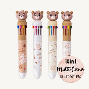 May include: Four multi-colour ballpoint pens with bear-shaped toppers. Each pen has a different design featuring a cartoon bear and the text "have a good day!" or "Cute Bear". The pens are labelled "10 in 1 Multi-Colour BALLPOINT PEN".