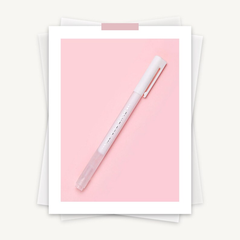 May include: A white highlighter pen with a clear tip and a silver clip, set against a soft pink background. The pen has subtle text along its side. The image is presented on a white paper background.