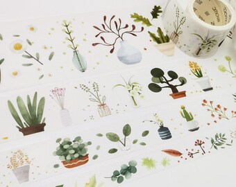 May include: Decorative washi tape featuring watercolor illustrations of potted plants, vases, and floral arrangements in shades of green, brown, and white. The tape is on a white background and is partially rolled.