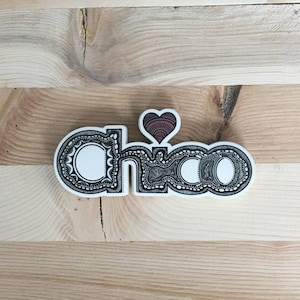 May include: A white sticker with the word "ciao" in black outlined letters with a decorative design. A small red heart is above the word.