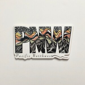 Puede incluir: Una pegatina en blanco y negro con las letras "PNW" en una fuente estilizada. Las letras est&aacute;n rellenas con un dise&ntilde;o de monta&ntilde;as y olas en tonos de verde, marr&oacute;n y naranja. El texto "Pacific Northwest" est&aacute; escrito debajo de las letras.