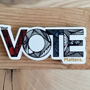 May include: A white sticker with the word "VOTE" in black outlined letters. Each letter is filled with a different patterned design. The "V" is red and white, the "O" is black and white, the "T" is blue and white, and the "E" is black and white. The sticker also says "Your" above the word "VOTE" and "Matters." below the word "VOTE".