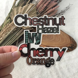 May include: A sticker with the words "Chestnut Hazel Ivy Cherry Orange" in a colorful, patterned font.