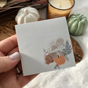 May include: A white card with a watercolor illustration of a pumpkin, leaves, and the word "Thankful".