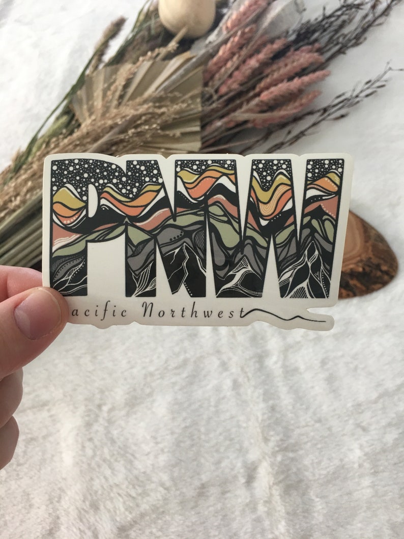 Puede incluir: Una pegatina con un gr&aacute;fico estilizado de las letras "PNW" en negro, blanco y tonos de marr&oacute;n y amarillo. Las letras est&aacute;n rellenas con un dise&ntilde;o de cordillera. El texto "Pacific Northwest" est&aacute; escrito debajo de las letras.