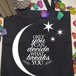 May include: Black tote bag with white text that reads "Only you can decide what breaks you". The text is surrounded by a crescent moon and stars.