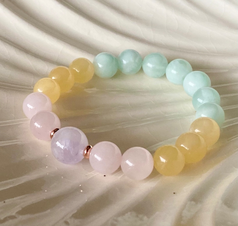 May include: A multi-colored beaded bracelet with pink, yellow, and green beads. The bracelet has a single lavender bead in the center.