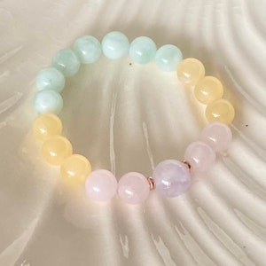 May include: A pastel-colored beaded bracelet with light green, yellow, and pink beads. The bracelet is made with natural stones and has a rose gold accent.