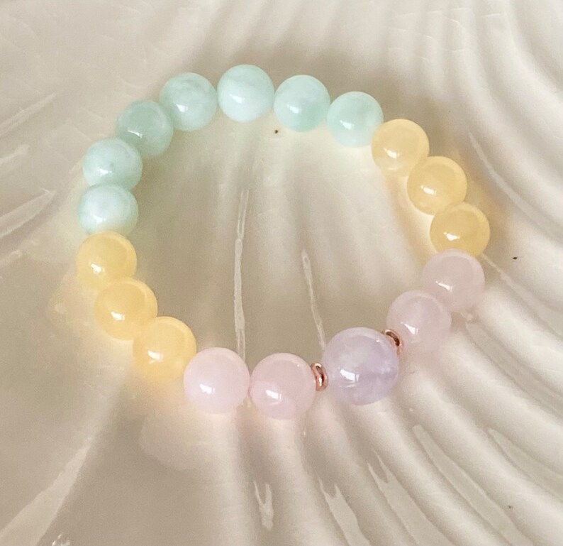 May include: A pastel-colored beaded bracelet with light green, yellow, and pink beads. The bracelet is made with natural stones and has a rose gold accent.