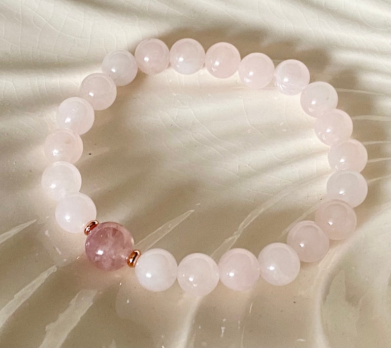 Pu&ograve; includere: Un braccialetto in quarzo rosa con dettagli in oro rosa. Il braccialetto &egrave; fatto di perline rotonde e ha un'unica perla di quarzo rosa pi&ugrave; grande al centro.