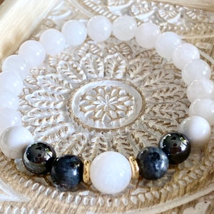 May include: White gemstone bracelet with black and grey beads and gold accents.