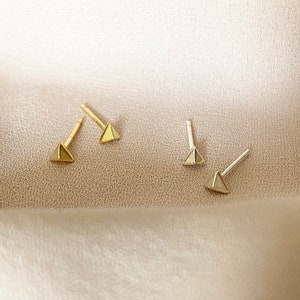 May include: Three pairs of triangle-shaped earrings in gold and silver. The earrings are small and delicate, and they would make a great gift for a friend or loved one.
