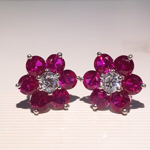 Peut inclure: Une paire de boucles d'oreilles &agrave; clous en forme de fleur. Chaque boucle d'oreille pr&eacute;sente une pierre centrale ronde et transparente entour&eacute;e de cinq pierres de couleur magenta. Les boucles d'oreilles sont serties dans un m&eacute;tal argent&eacute;.