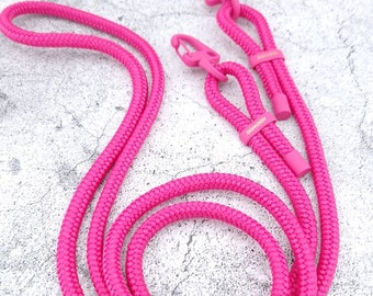May include: A pink rope lanyard with two metal clasps. The lanyard is coiled and the clasps are visible.