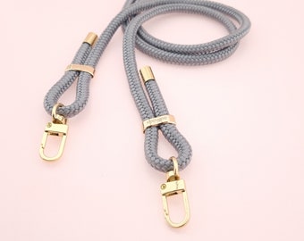 May include: A gray rope phone strap with gold hardware and the word "deevee" engraved on the hardware.
