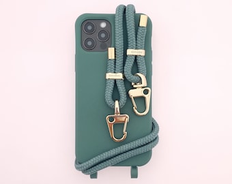 May include: A teal green phone case with a matching teal green phone strap with gold hardware and the word "konovaa" printed on the strap.