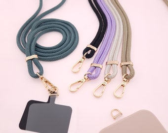 May include: Five phone straps with gold clasps and a clear phone case with a gold clasp. The straps are in various colors: teal, black, lavender, cream, and beige.