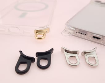 May include: Three different phone case strap attachments. One is gold, one is silver, and one is black.