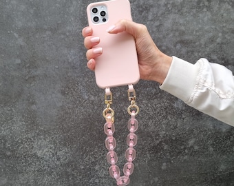 Könnte beinhalten: Eine rosa Handyhülle mit einem durchsichtigen rosa Kettenband. Die Hülle hat einen Ausschnitt für das Kameraobjektiv und einen goldenen Akzent.