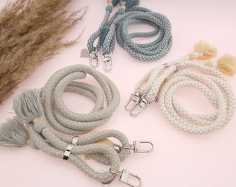 May include: Three sets of braided cotton cords with tassels and metal clasps. The cords are in shades of light blue, gray, and cream.
