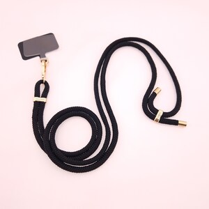 May include: Black lanyard with a gold clasp and a black rectangular tag. The lanyard is made of a thick, braided rope.