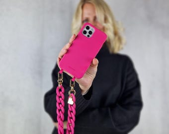May include: A bright pink phone case with a gold chain strap and a heart charm. The case is made of silicone and has a smooth finish.