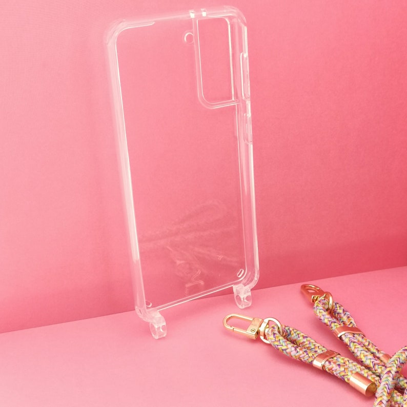 Pu&ograve; includere: Una custodia per telefono trasparente con un rialzo per la fotocamera e un cinturino per telefono intrecciato colorato con accessori dorati.