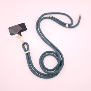 May include: A teal blue rope lanyard with gold metal hardware. The lanyard has a detachable badge holder.