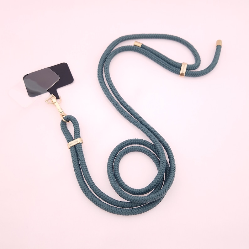May include: A teal blue rope lanyard with gold metal hardware. The lanyard has a detachable badge holder.
