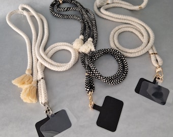 May include: Three white and black patterned lanyards with black and clear plastic ID card holders. The lanyards are made of rope and have a tassel on one end.