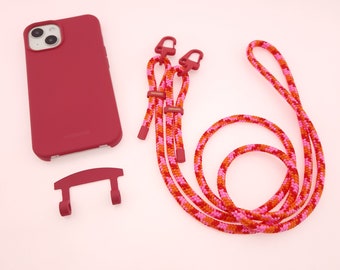 May include: A red phone case with a matching red phone strap. The strap is made of a braided rope with pink and orange accents. The case has a small, red, plastic attachment for the strap.