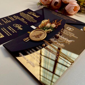 K&ouml;nnte beinhalten: Goldene Spiegel-Hochzeitseinladung mit schwarzem Umschlag und goldenem Siegellack. Die Einladung lautet "Open Hearts to Celebrate the Marriage of Verrick & Chante Johnson, November 10, 2023, In the Evening, Andelery Hotel, 445 Pacific Highway, San Diego, CA 92108, Reception to Follow."