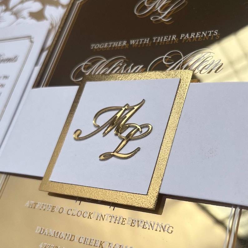 K&ouml;nnte beinhalten: Goldene Hochzeitseinladung mit wei&szlig;en Akzenten. Die Einladung zeigt ein goldenes Monogramm der Buchstaben "M" und "L" sowie den Text "Together with their parents Melissa Evelyn".