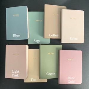 Peut inclure: Dix carnets de notes de couleurs diff&eacute;rentes avec le mot "NOTES" imprim&eacute; en or sur la couverture. Les carnets sont dispos&eacute;s en deux rang&eacute;es de cinq. Les couleurs sont bleu, sauge, caf&eacute;, beige, rose p&acirc;le, beige, vert et or rose.