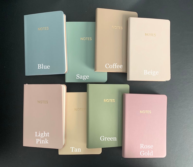 Peut inclure: Dix carnets de notes de couleurs diff&eacute;rentes avec le mot "NOTES" imprim&eacute; en or sur la couverture. Les carnets sont dispos&eacute;s en deux rang&eacute;es de cinq. Les couleurs sont bleu, sauge, caf&eacute;, beige, rose p&acirc;le, beige, vert et or rose.