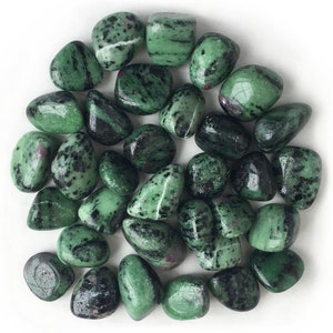 May include: A collection of tumbled green and black gemstones. The stones are smooth and polished, with a variety of patterns and markings.