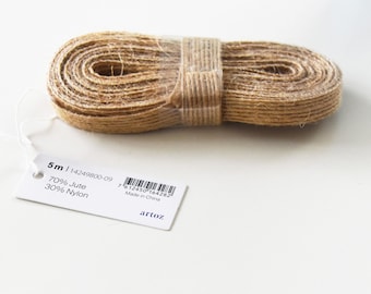 Puede incluir: Un rollo de cinta de yute marrón natural, enrollada y asegurada con plástico transparente. Una etiqueta blanca muestra el texto "5m | 14249800-09", "70% Jute" y "30% Nylon". Ideal para manualidades y decoración.