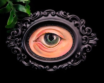 Hand painted eye, in a black oval ornate frame. Gothic art.