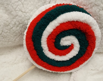 May include: A red, white, and green yarn lollipop with a wooden stick. The lollipop is shaped like a spiral.