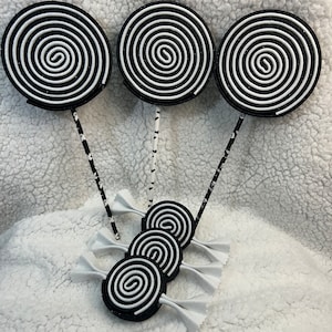 May include: Three black and white swirl lollipop decorations with black and white striped sticks. Three smaller black and white swirl lollipop decorations are also included.