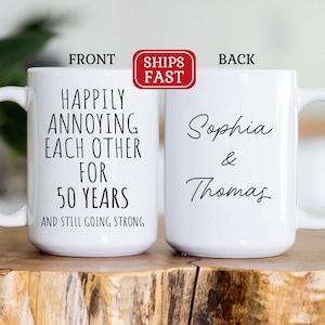May include: White ceramic coffee mug with black text that reads "Happily annoying each other for 50 years and still going strong". The back of the mug has black text that reads "Sophia & Thomas".