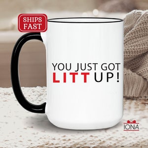May include: White ceramic coffee mug with a black handle and black rim. The mug has the text "YOU JUST GOT LIT UP!" in black and red lettering.