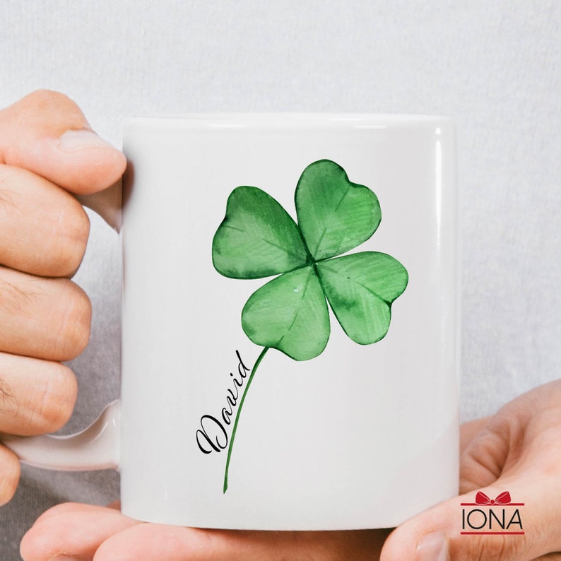 May include: White ceramic mug with a green four-leaf clover and the name "David" written in cursive.