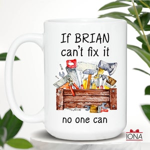 May include: White ceramic mug with a handle, featuring a watercolor illustration of a wooden toolbox filled with tools. The mug has the text "If BRIAN can't fix it no one can" in black.