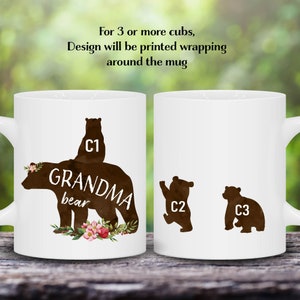 May include: White ceramic mug with a brown silhouette of a bear with the text "GRANDMA bear" and a smaller bear on top. The mug also has a floral design with pink flowers. The text "C1" is on the smaller bear, and the text "C2" and "C3" are on two smaller bears on the other side of the mug.