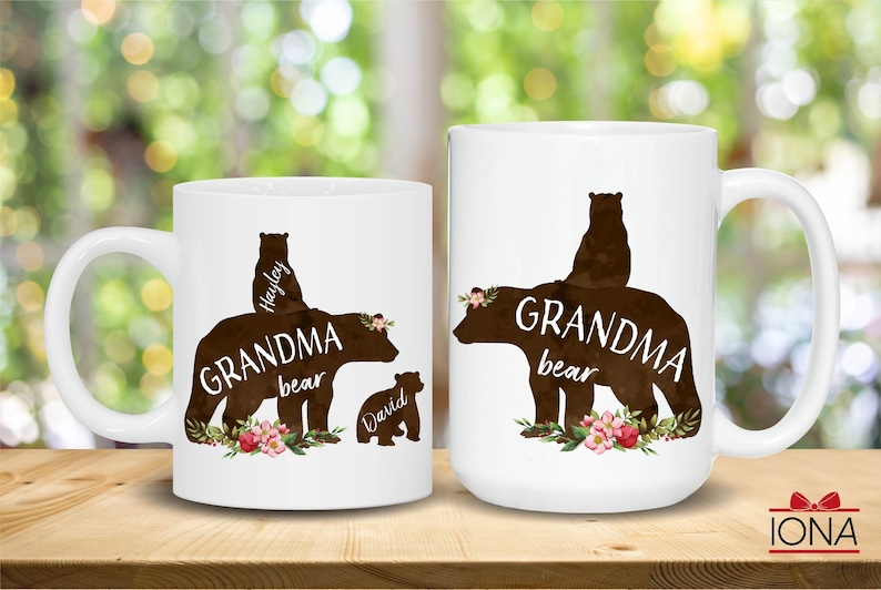May include: Two white ceramic mugs with black bear silhouettes and floral accents. The text on the mugs reads "Grandma bear" with the names "Hayley" and "David" on the smaller bears.
