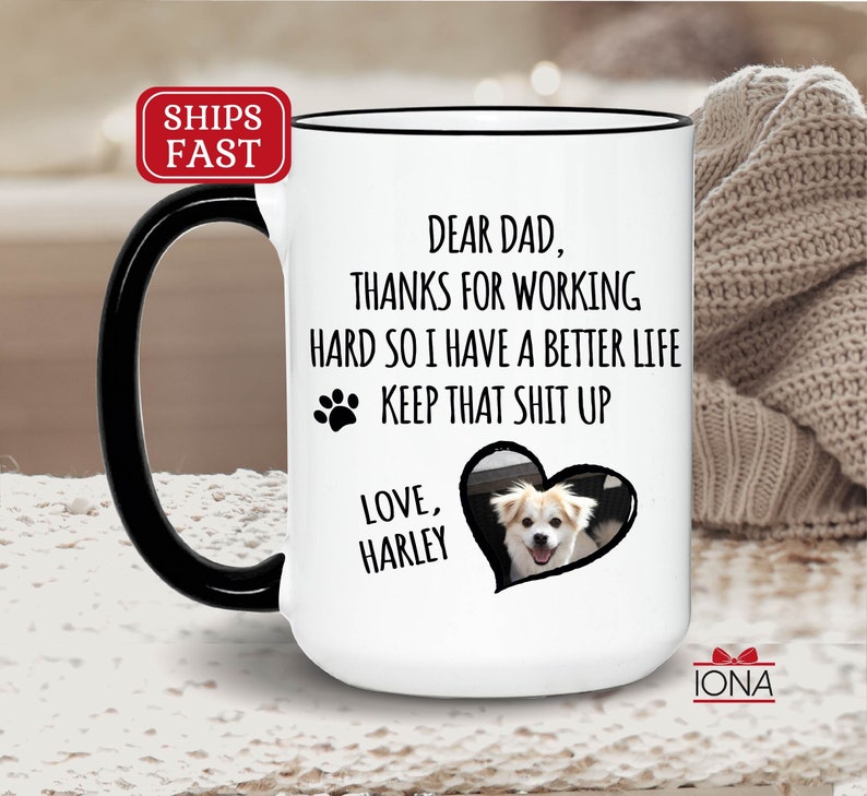 May include: White ceramic coffee mug with a black handle. The mug has a black rim and a black heart-shaped image with a dog inside. The text on the mug reads "Dear Dad, Thanks for working hard so I have a better life. Keep that shit up. Love, Harley."