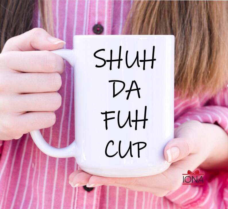 K&ouml;nnte beinhalten: Wei&szlig;e Keramiktasse mit schwarzem Text, der "SHUH DA FUH CUP" lautet.